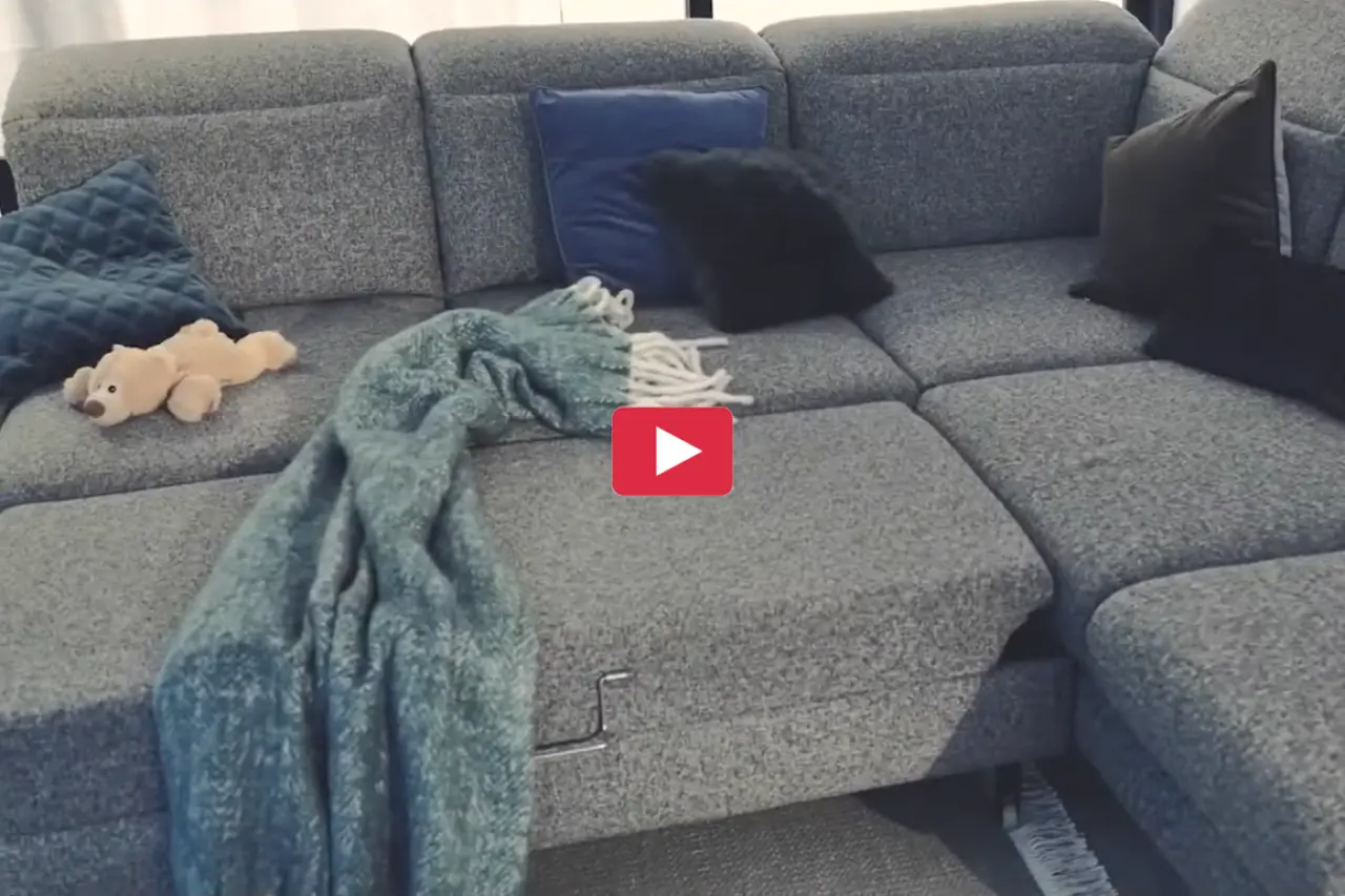Großes modulares Sofa in Grau mit ausgeklappter Liegefläche, Kissen und Decke. Wohnlandschaft mit Schlaffunktion für gemütliches Wohnen, Entspannung und flexible Nutzung im modernen Wohnzimmer.
